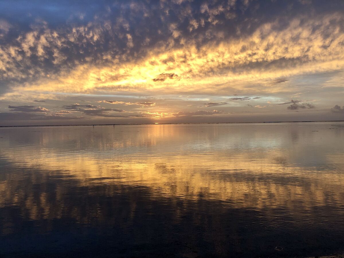 A calm body of water reflecting the sky during sunset.