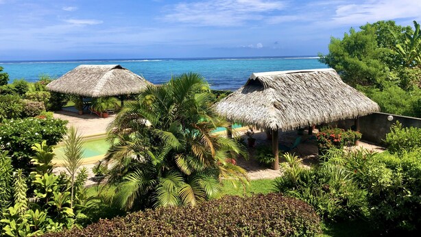 Un complexe hôtelier tropical doté de bungalows aux toits de chaume, d’une piscine et d’une végétation luxuriante.