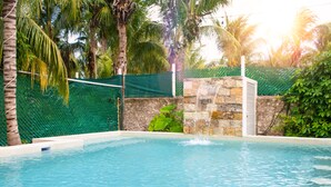 A swimming pool with a stone wall and a water feature. - Cacao Cabin, Only Adults (El Cuyo)