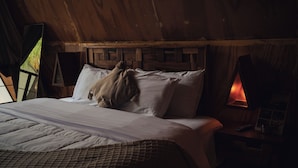 A wooden cabin-style room with a bed, a nightstand, and a wall-mounted lamp. - Cacao Cabin, Only Adults (El Cuyo)