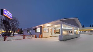 Un hotel con un'area esterna coperta, una targa e terreno innevato.
