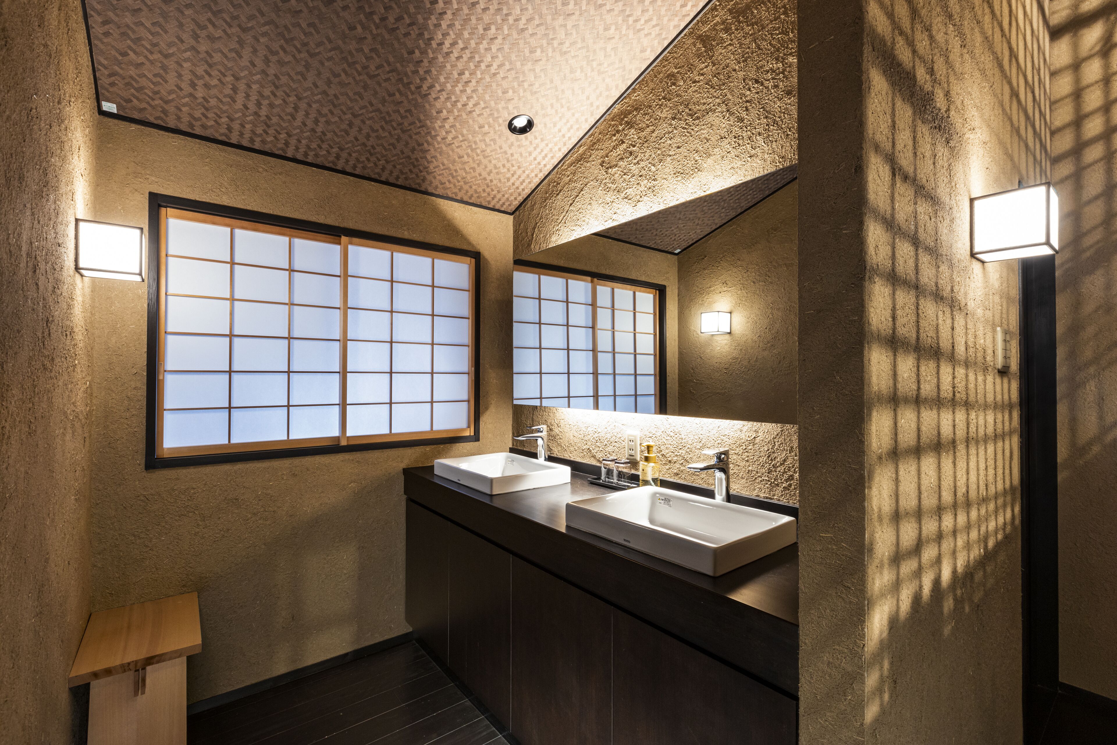 Un baño moderno con dos lavamanos, un espejo grande y una ventana con diseño de cuadrícula.