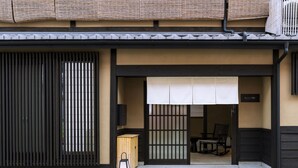 Ein traditionelles japanisches Gebäude mit einer Schiebetür, einer Holzkiste und einem Laternen auf dem Boden.