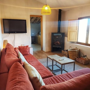 Un salon avec un canapé rouge, un téléviseur, une cheminée et une fenêtre.