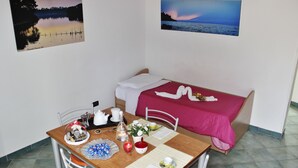 A room with a bed, a dining table with a red tablecloth, and two framed pictures on the walls. - Apartment in old building (Santa Cesarea Terme)