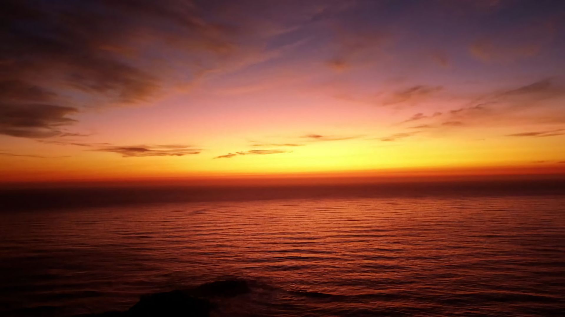 A sunset over a body of water with a clear horizon.
