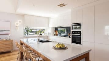A modern kitchen with white cabinetry, a central island, and a dining area with wicker chairs.