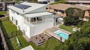 A modern two-story house with a solar panel, a swimming pool, and a deck.