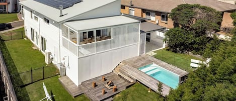 A modern two-story house with a solar panel, a swimming pool, and a deck.