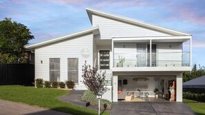 Ett modernt hus i två våningar med en balkong, ett garage och en välskött gräsmatta.