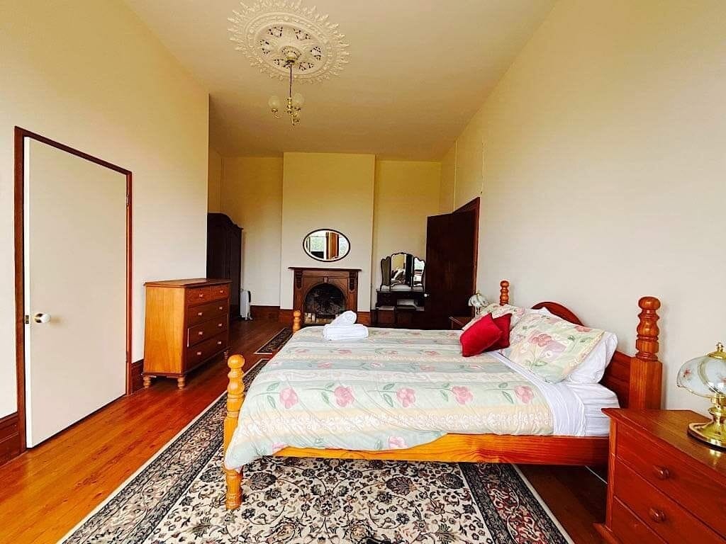 A bedroom with a bed, wooden dresser, and a mirror.