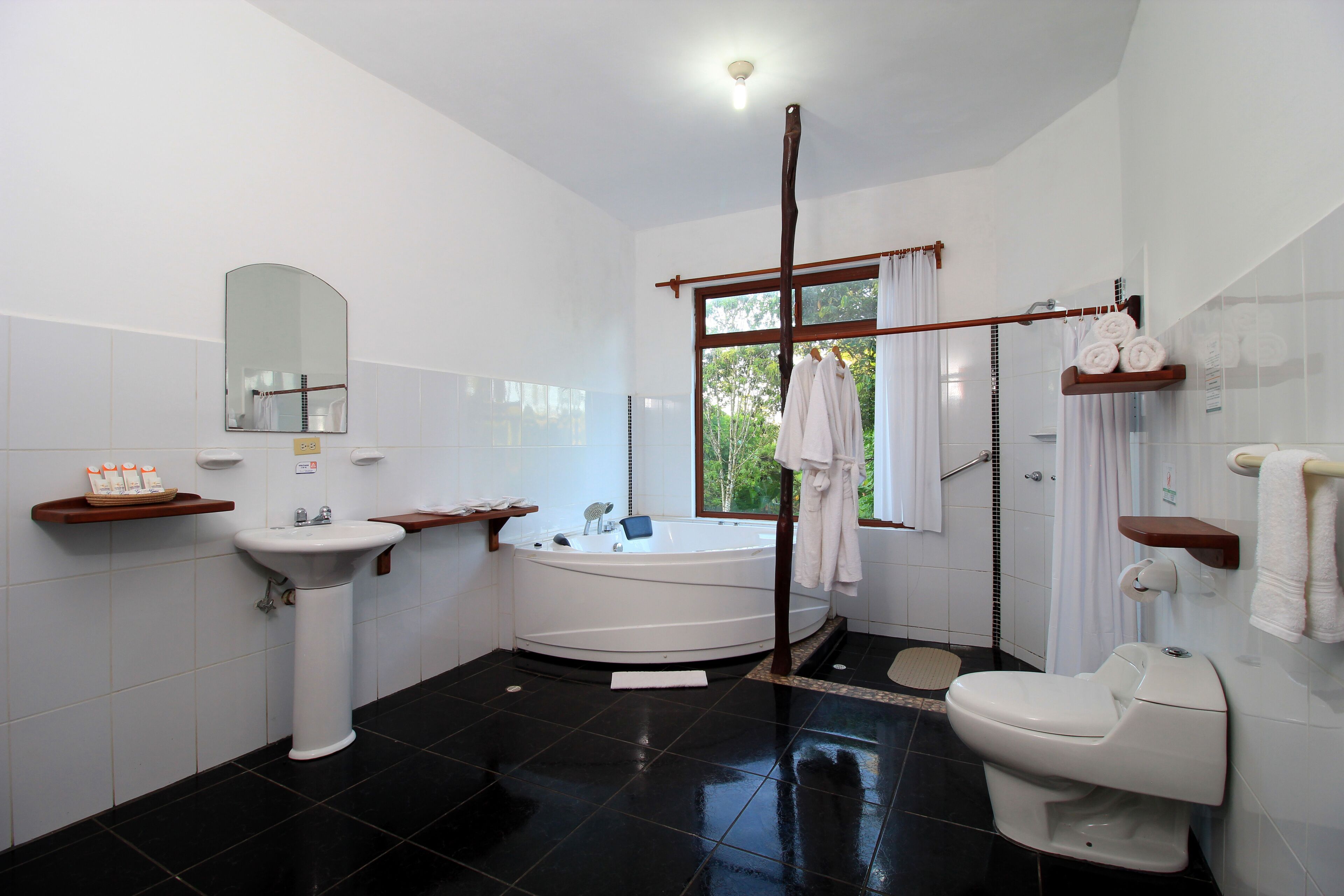 A modern bathroom with a bathtub, toilet, sink, and a large mirror.