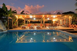 A poolside area with lounge chairs and a covered seating area. - Natura Gardens Galápagos Hotel (Bella Vista)