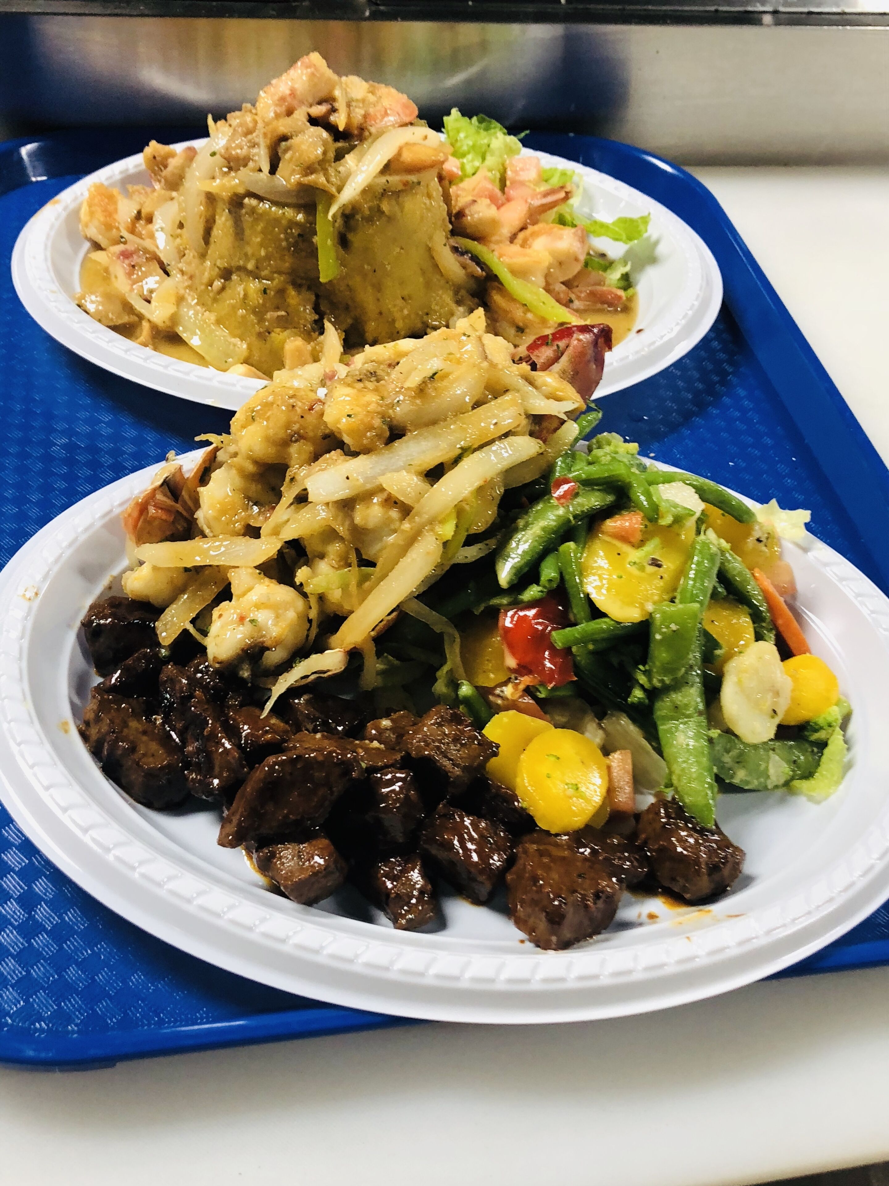 Two paper plates with food on a blue tray.