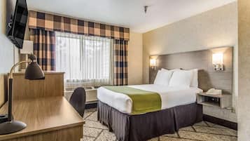 Relax in a stylish room with a made bed, desk, flat-screen TV, and comfortable seating area.