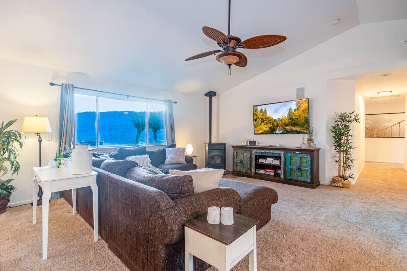 A living room with a sofa, a coffee table, a TV, a fireplace, and a view of the outdoors.
