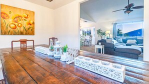 Un comedor con una mesa de madera, elementos decorativos blancos y un cuadro de flores.