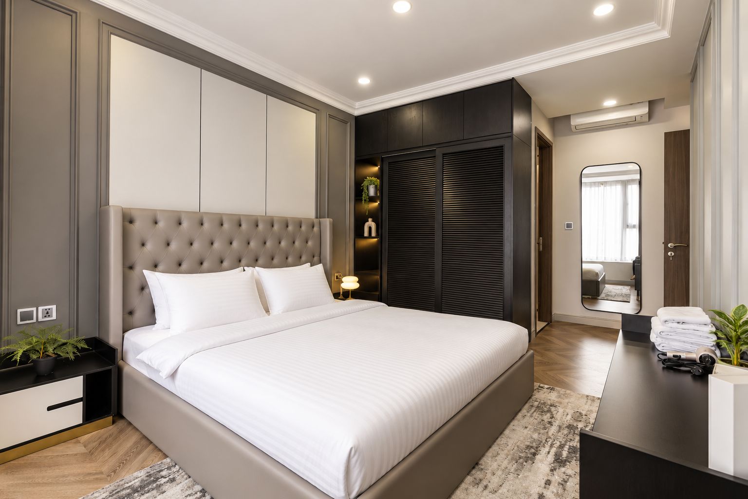 Une chambre à coucher moderne avec un grand lit, une armoire, une table de chevet et un miroir.