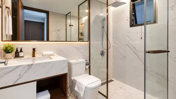 A modern bathroom with a marble countertop, a glass shower enclosure, and a wooden vanity.