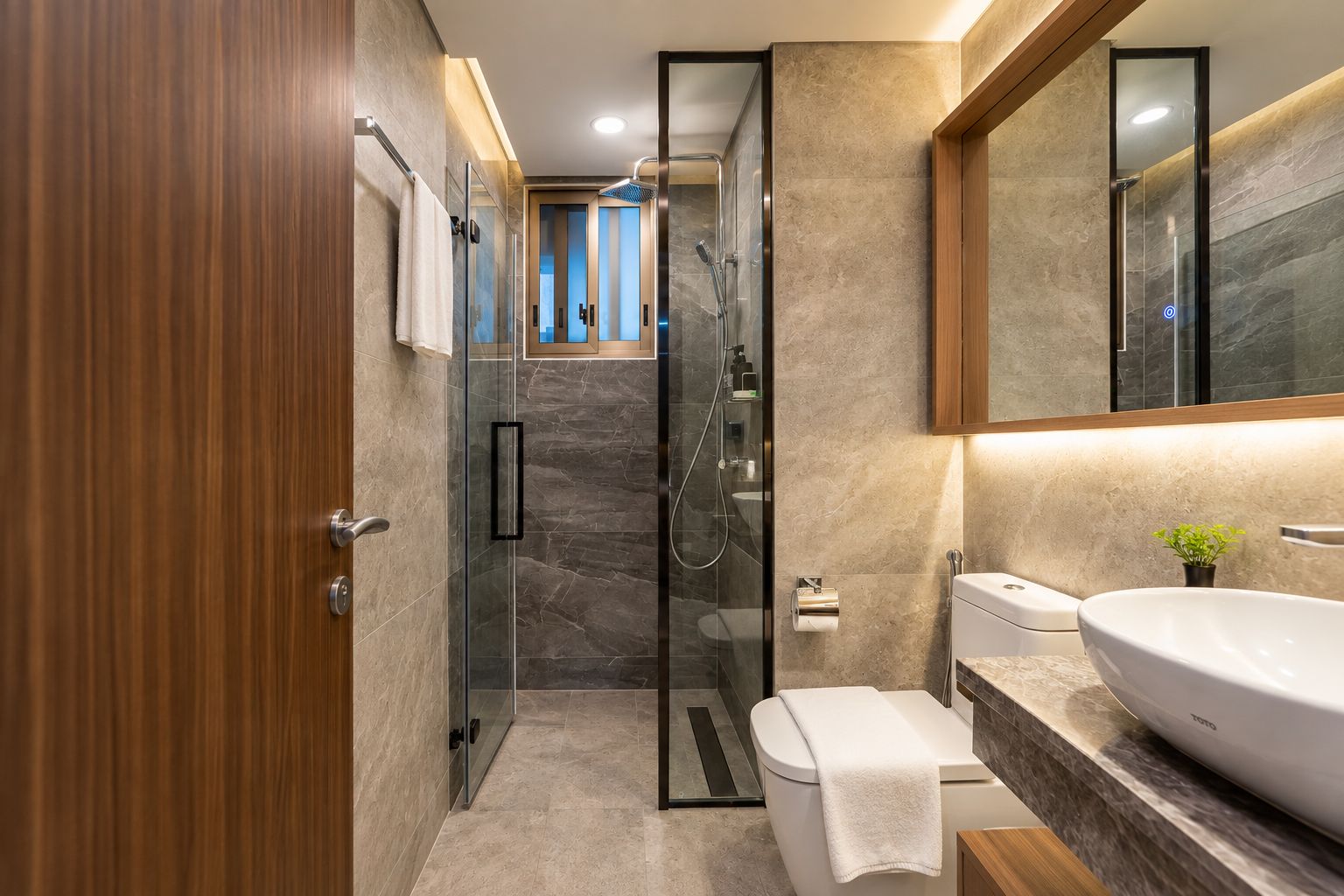 A modern bathroom with a glass-enclosed shower, a white toilet, and a large sink with a mirror above it.