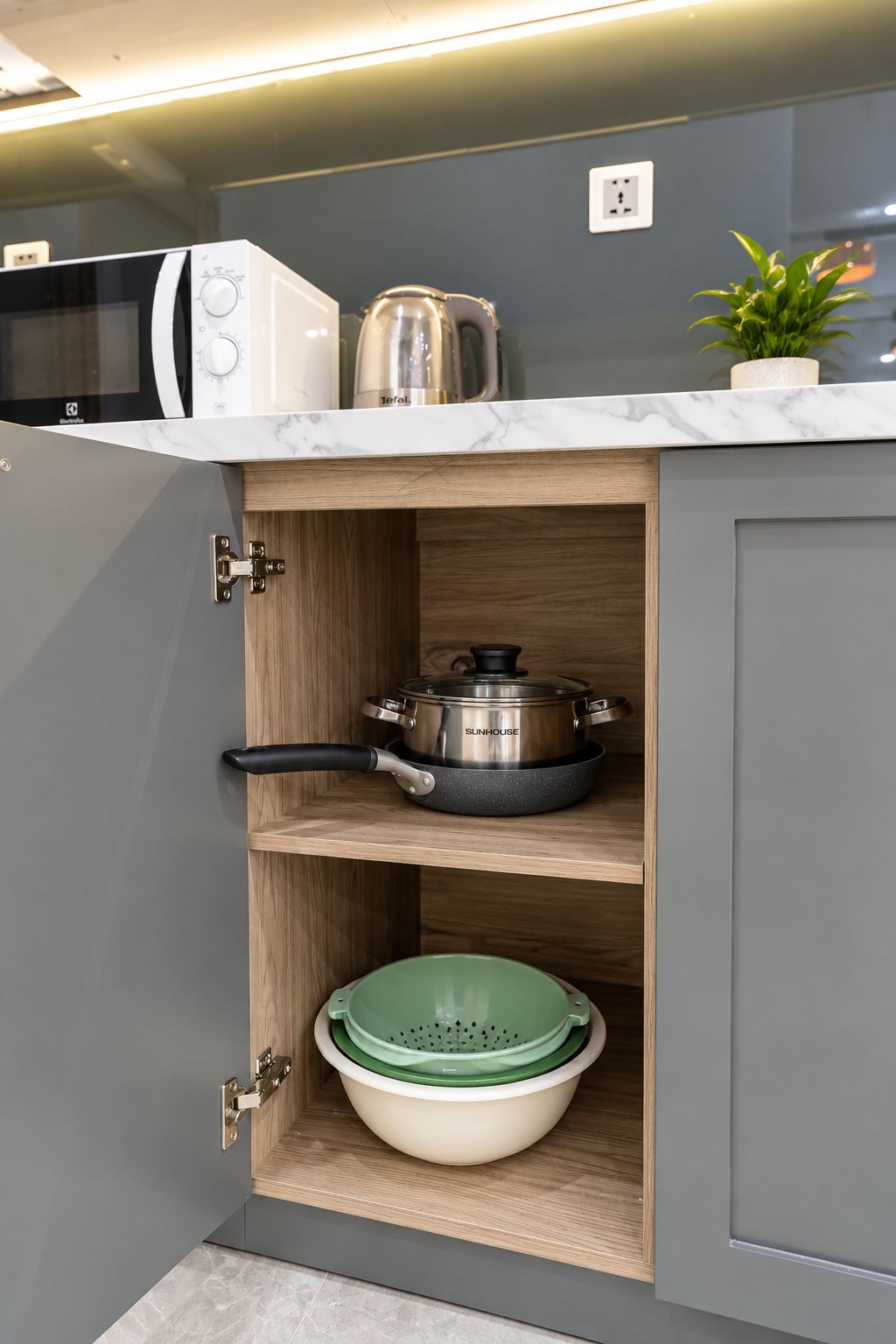 A kitchen with a microwave, a kettle, and a pot on the countertop.