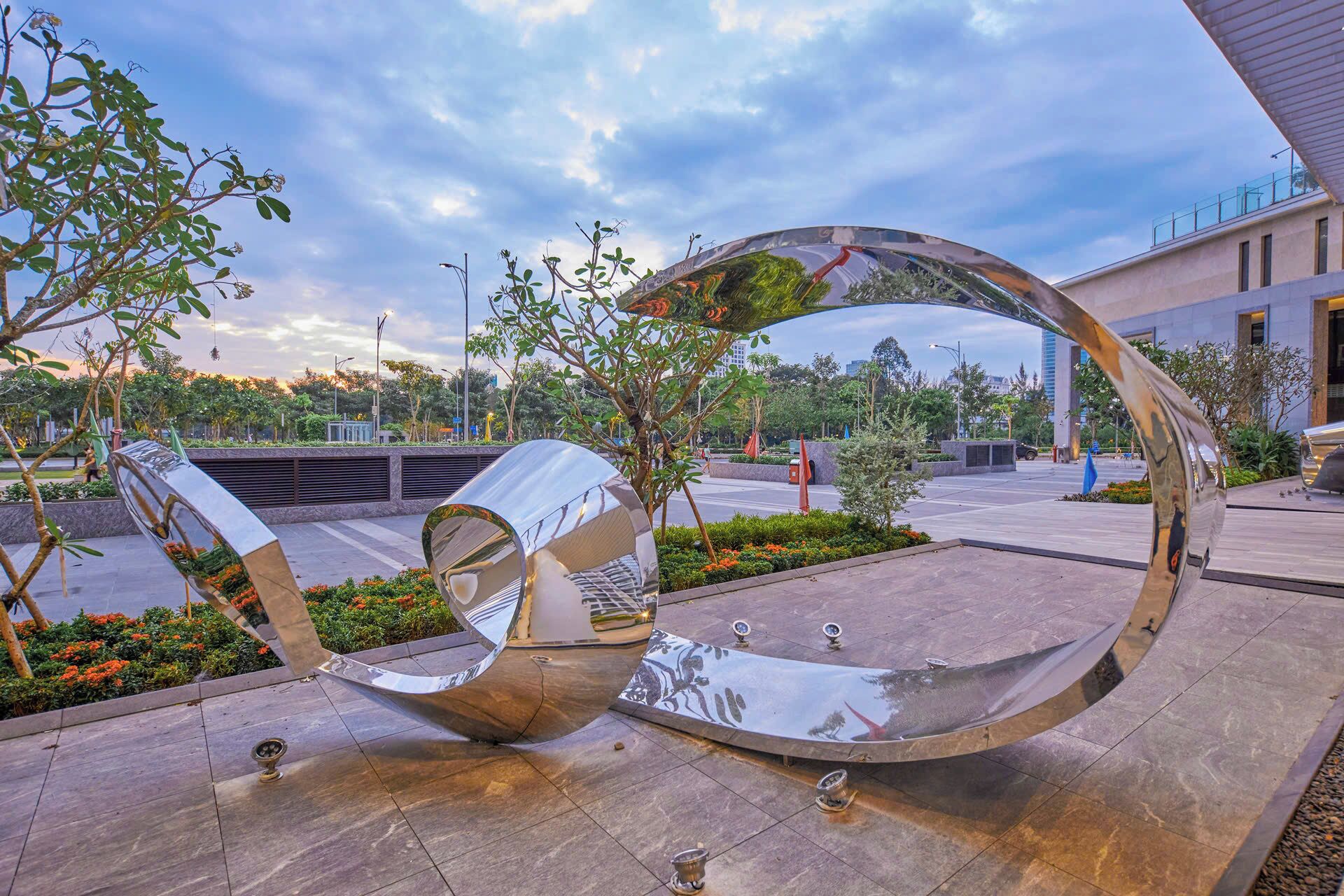 Une sculpture moderne à la surface réfléchissante, installée dans une place publique.
