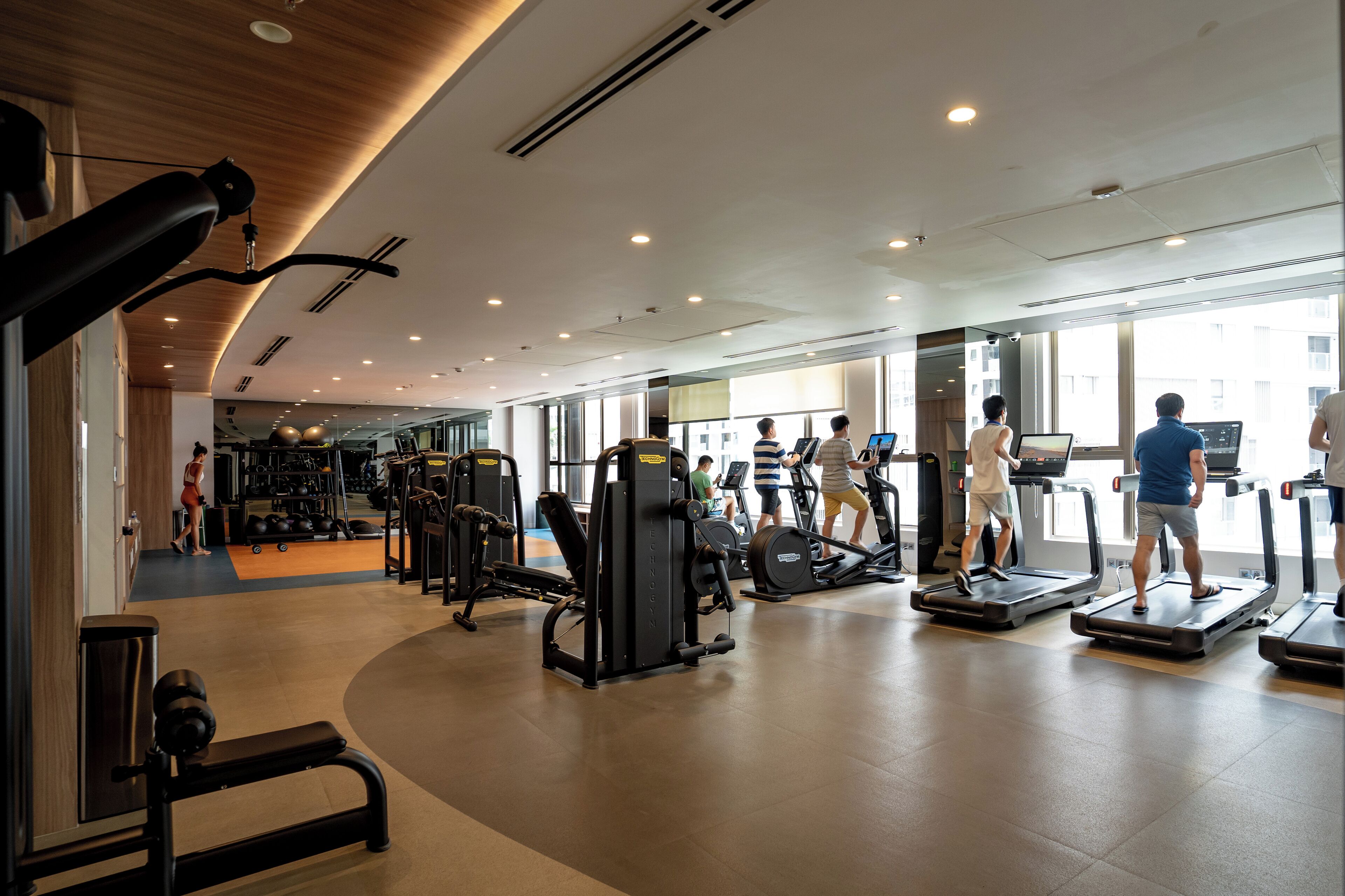 A gym with treadmills, weight machines, and a mirror wall.