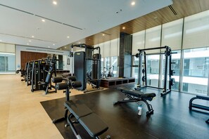 Un gimnasio moderno con diversos equipos de ejercicio, amplias ventanas y un diseño limpio y espacioso.