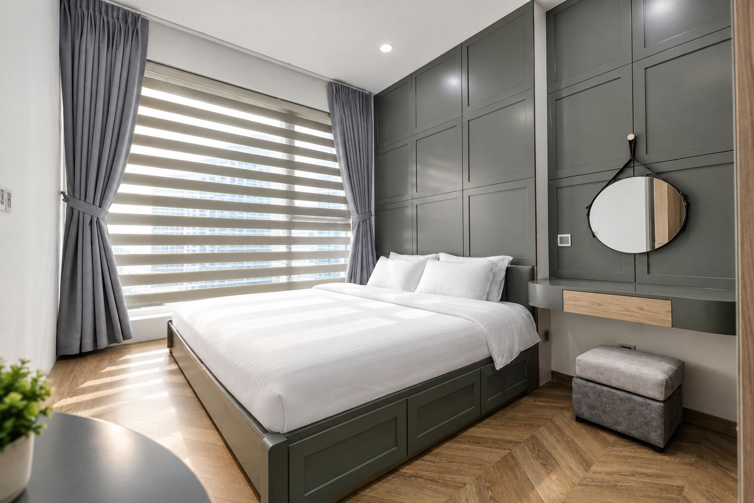 Une chambre moderne avec un lit, des rideaux gris, un miroir rond et un petit banc.