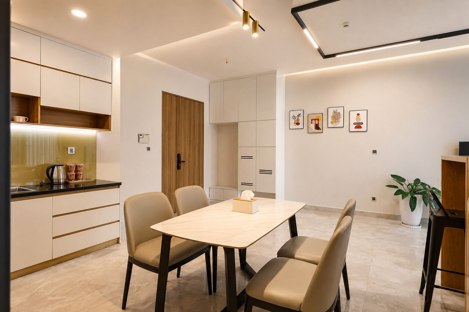 A modern kitchen with a dining area, featuring a table with chairs, a coffee machine, and a potted plant.