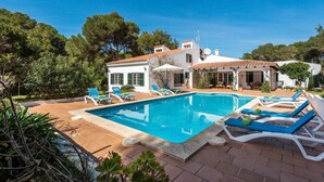 A villa with a swimming pool, lounge chairs, and a garden. - 185 Sud  relax and enjoy Menorca (Son Parc)