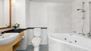 Casa de banho moderna com lavatório, sanita e banheira brancos.