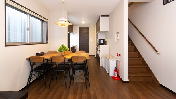Una cocina moderna con comedor, piso de madera y una escalera.