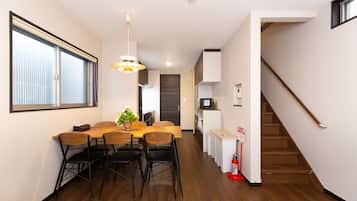A modern kitchen with a dining area, wooden flooring, and a staircase.