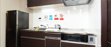 A modern kitchen with a built-in refrigerator, dishwasher, and oven. There are several safety signs on the wall.