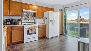 Una cocina moderna con armarios de madera, un refrigerador blanco, un microondas y una estufa.