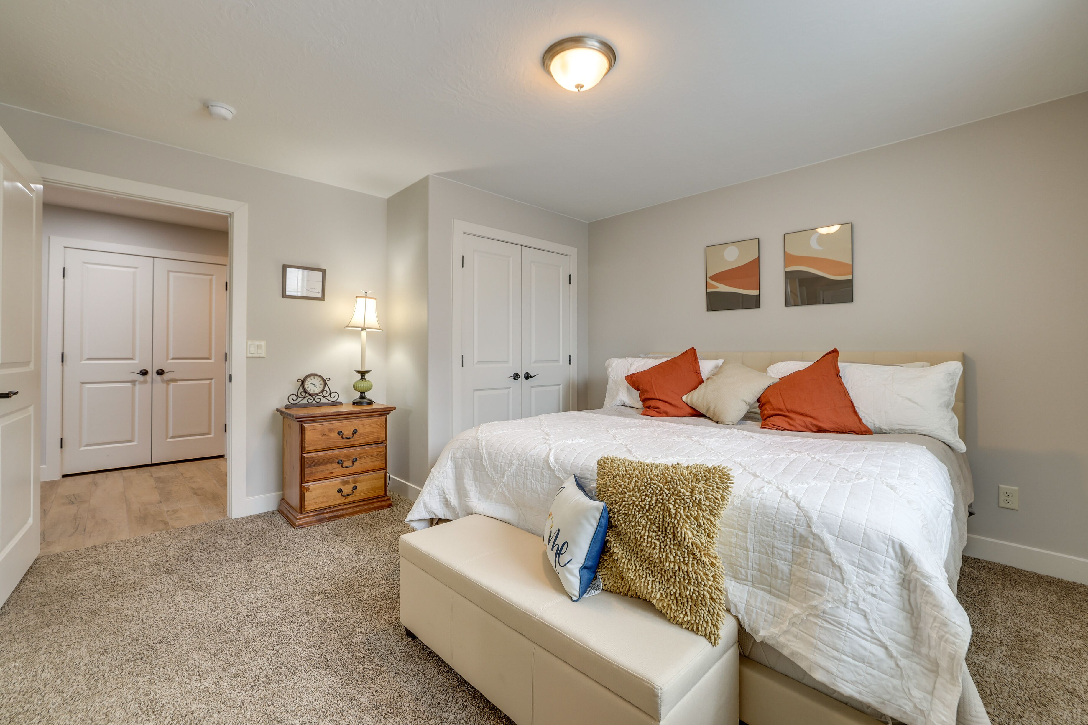 A bedroom with a bed, a nightstand, a dresser, and two doors.