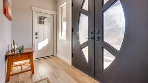 A hallway with a wooden bench, a white door, and a dark door with geometric glass panels.