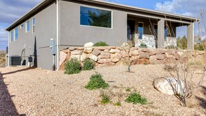A modern house with a stone foundation, large windows, and a gravel driveway.