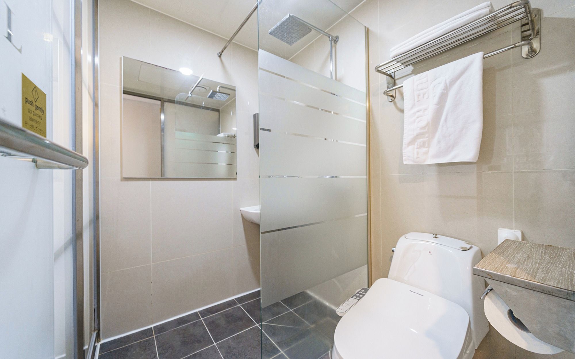A bathroom with a glass shower enclosure, a toilet, and a sink.