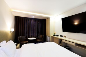 Relax in a spacious room with a large bed, flat-screen TV, and separate seating area.