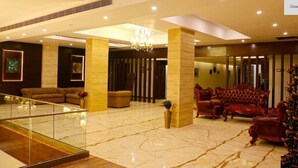 A spacious lobby with marble flooring, a grand chandelier, and classic leather sofas. - Tiaraa Hotels & Resorts (Ramnagar)