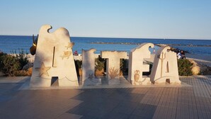Un paseo marítimo junto al mar con esculturas abstractas y vistas al océano.