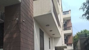 A residential building with a covered walkway, potted plants, and a visible door. - CWR Stays (Noida)