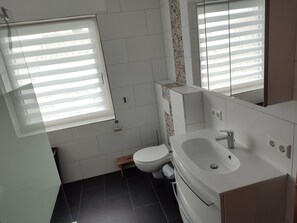 Modern bathroom with a clean design, featuring a white sink, toilet, and patterned tile walls.