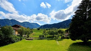 A rural landscape with a house, green fields, and mountains in the background. - Haus am Weißbach - Vacation in the Pfronten Valley (Pfronten)