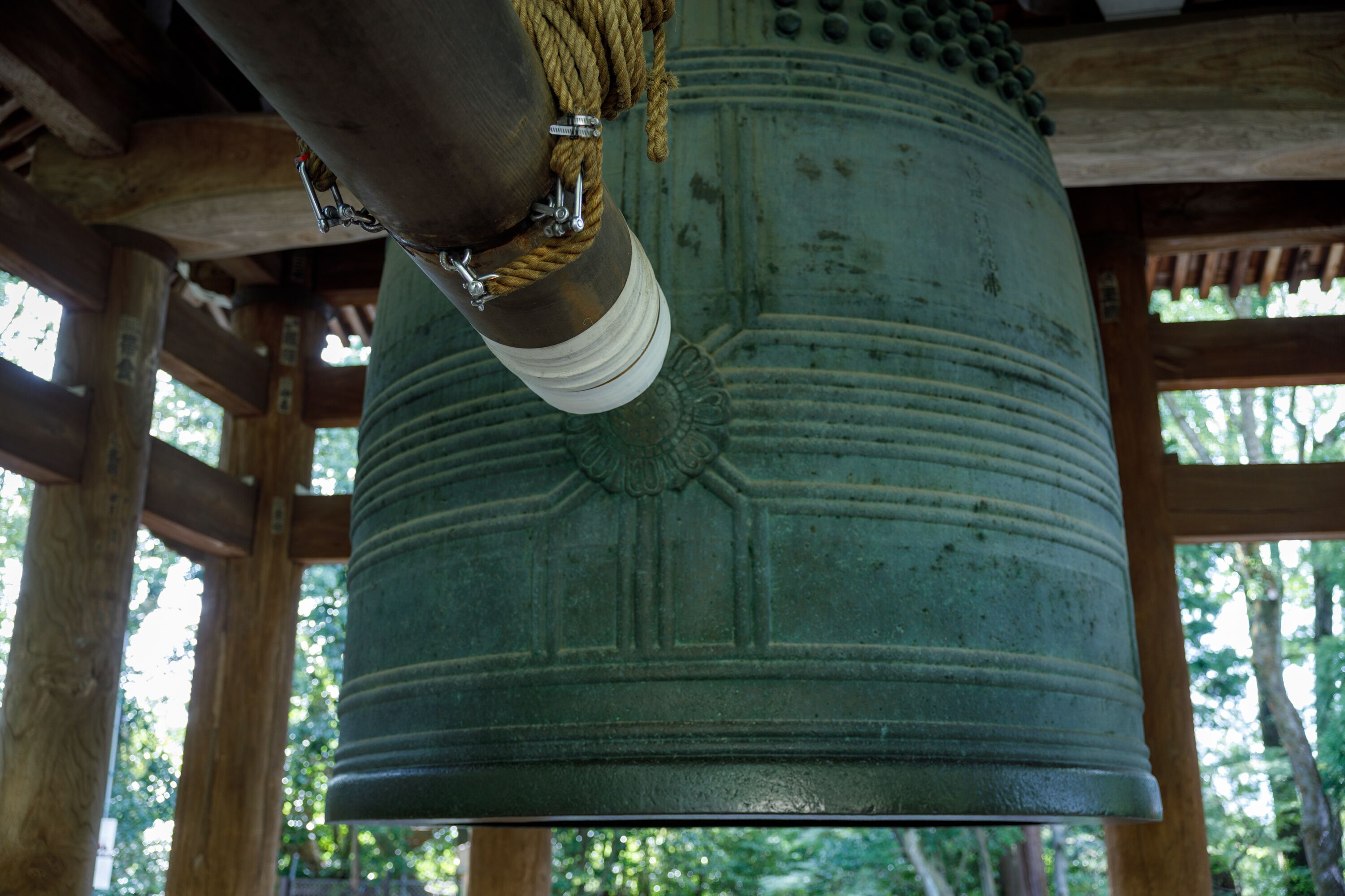 A large bell hanging from a wooden structure with ropes and metal fixtures.