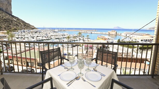 A balcony with a table set for four, overlooking a marina and a coastal town. - A84 CALPE TOWER 3-10 (Calpe)