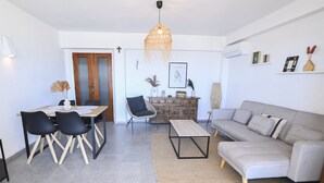 A modern living room with a grey sofa, a dining table with chairs, a hanging light fixture, and a wooden cabinet. - A84 CALPE TOWER 3-10 (Calpe)