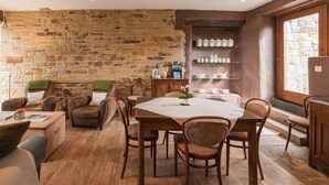 A rustic dining area with a stone wall, wooden furniture, and a view of the kitchen.